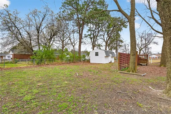 a backyard of a house with large trees and parked