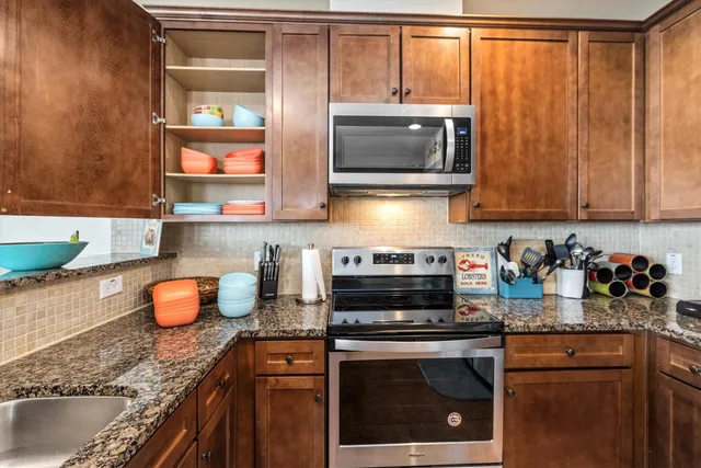 a kitchen with granite countertop a refrigerator and a stove top oven