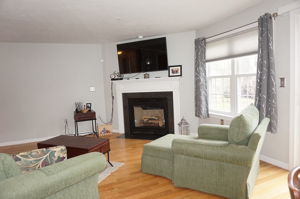 103 Bridle Cross Road, Unit 103 Fitchburg, MA 01420 - Photo 12 of 36 a living room with furniture a flat screen tv and a fireplace