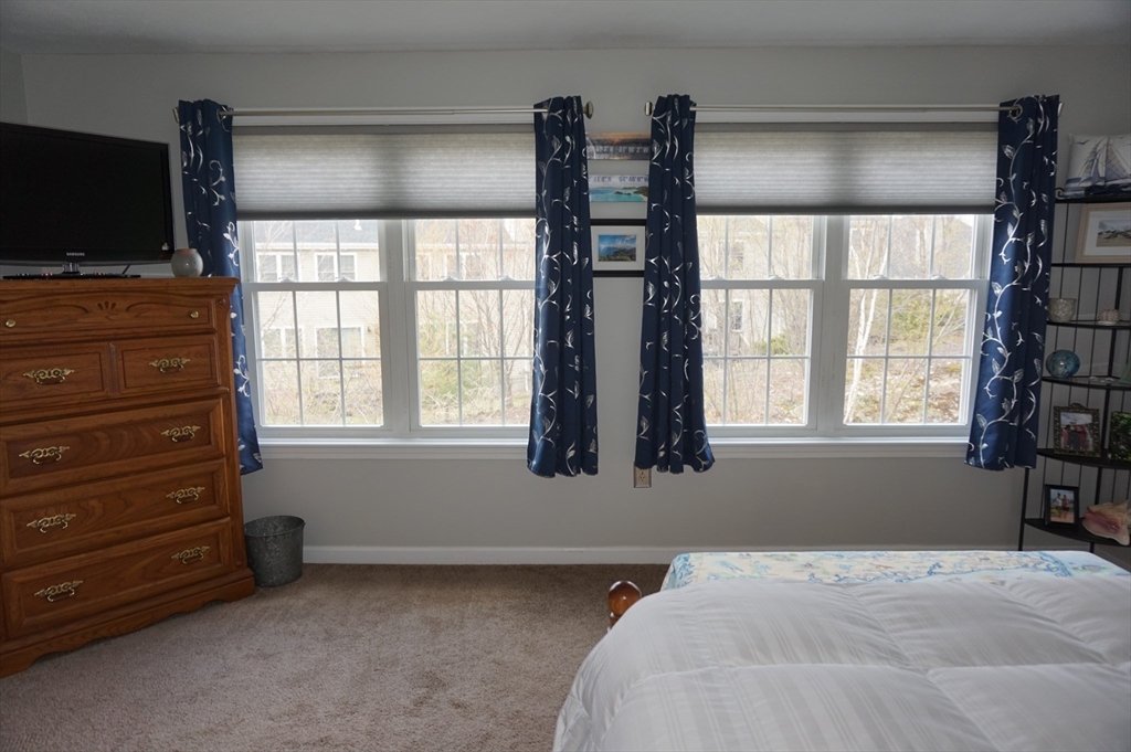 103 Bridle Cross Road, Unit 103 Fitchburg, MA 01420 - Photo 27 of 36 a bedroom with a bed and a flat tv screen on a dresser
