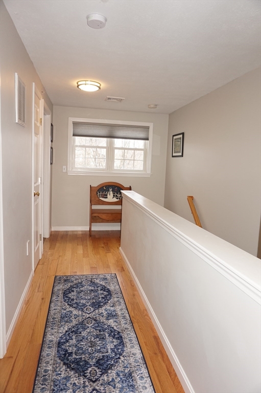 103 Bridle Cross Road, Unit 103 Fitchburg, MA 01420 - Photo 28 of 36 a hallway with bed and wooden floor