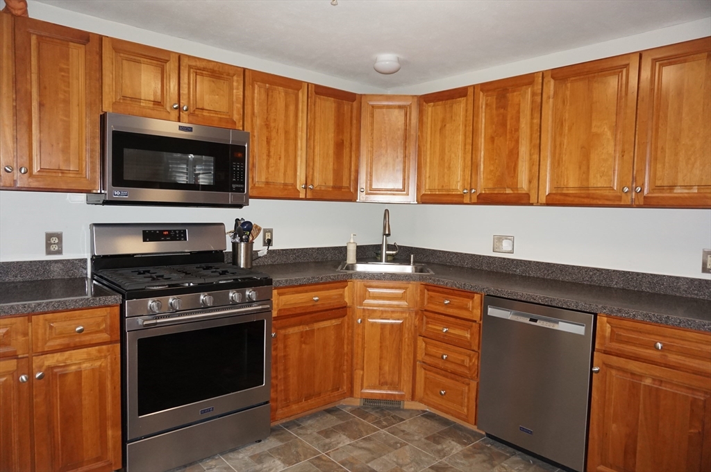 103 Bridle Cross Road, Unit 103 Fitchburg, MA 01420 - Photo 6 of 36 a kitchen with granite countertop a stove top oven microwave and cabinets