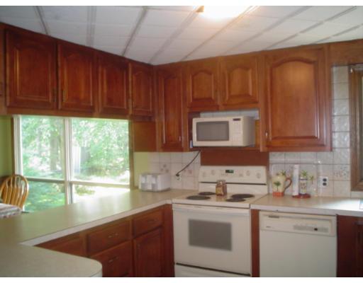 29 Broad Road Dracut, MA 01826 - Photo 8 of 16 a kitchen with stainless steel appliances wooden cabinets a stove a sink and a microwave