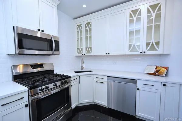a kitchen with stainless steel appliances white cabinets and stove top oven