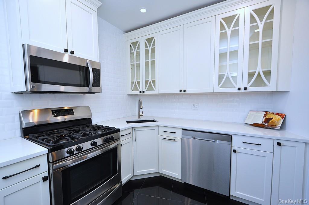 a kitchen with stainless steel appliances white cabinets and stove top oven