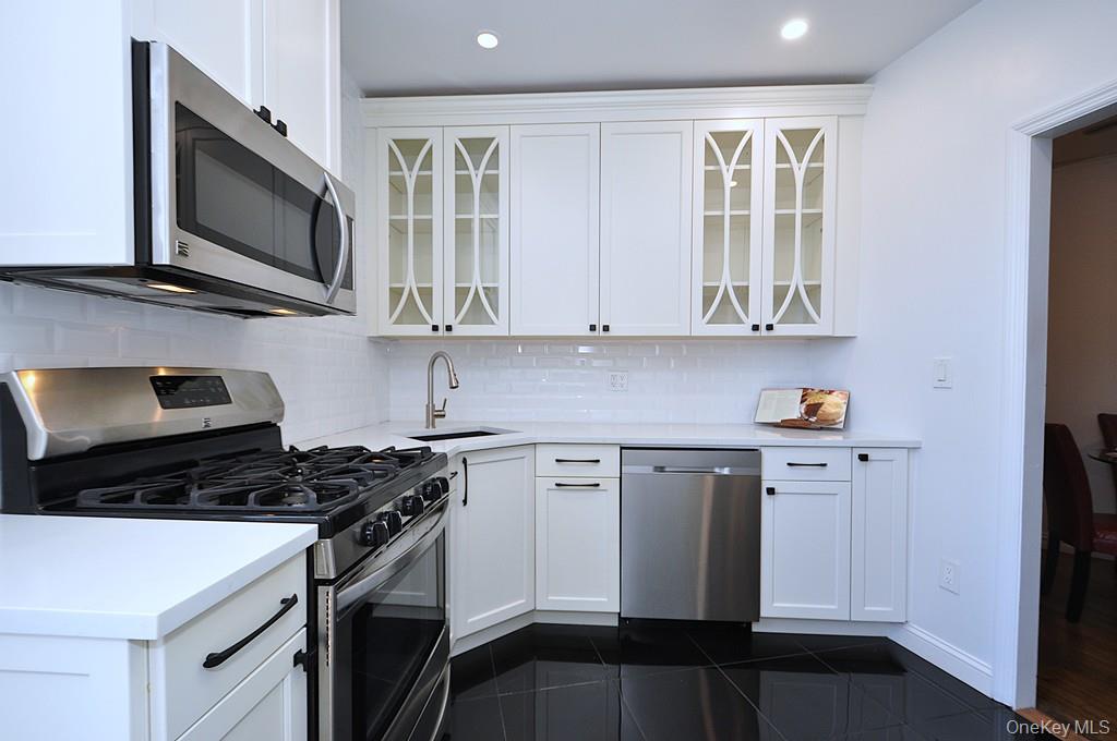 949 Palmer Road, Unit 2G Bronxville, NY 10708 - Photo 12 of 40 a kitchen with stainless steel appliances granite countertop white cabinets granite counter tops and a window