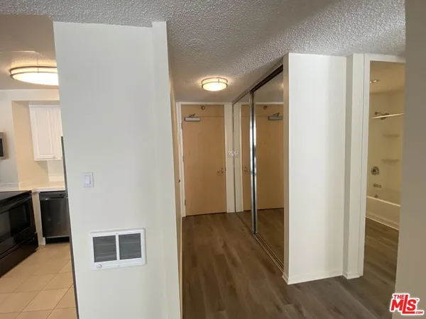 a view of a hallway with wooden floor and a bathroom