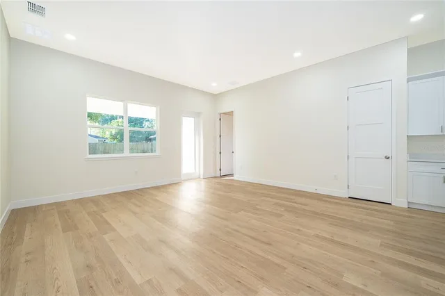 an empty room with wooden floor and windows