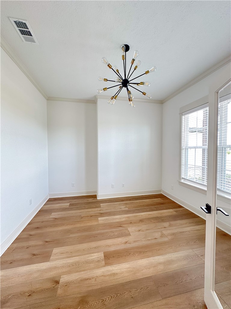 3201 Hunters Crossing Bryan, TX 77808 - Photo 20 of 40 Unfurnished room with a chandelier, light wood finished floors, ornamental molding, and a textured ceiling