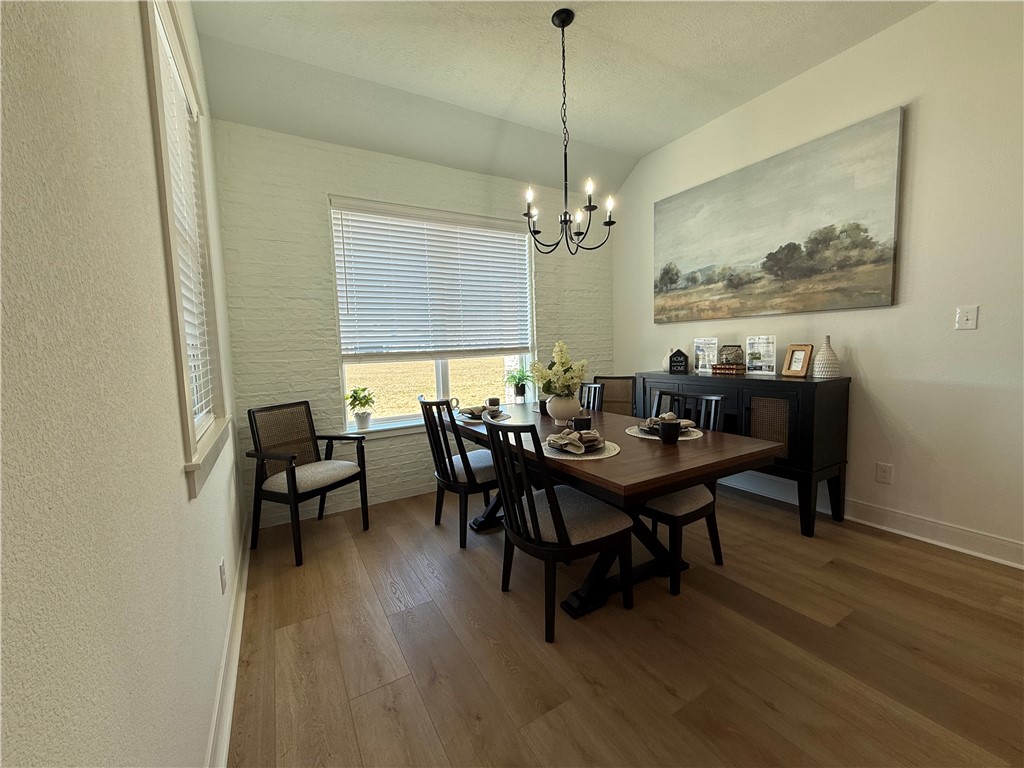 3201 Hunters Crossing Bryan, TX 77808 - Photo 26 of 40 Dining space featuring wood finished floors, a chandelier, and soaring ceiling and natural lighting from nice large windows