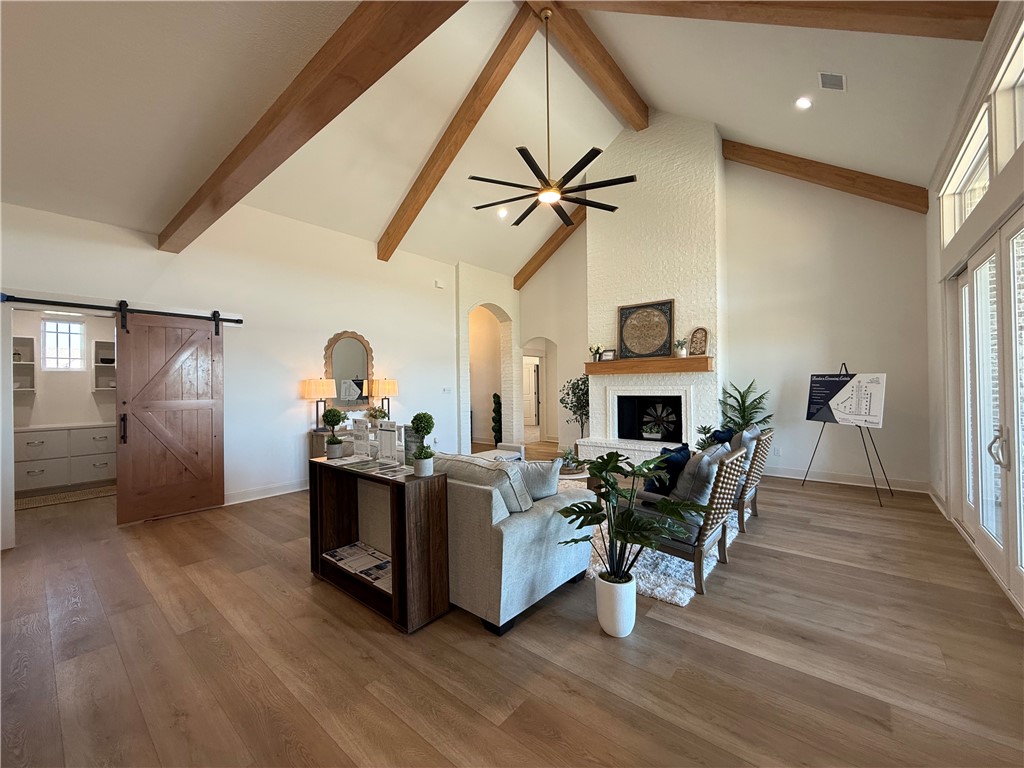 3201 Hunters Crossing Bryan, TX 77808 - Photo 32 of 40 Living area featuring a barn door, light wood-style flooring, arched walkways, vaulted ceiling, and ceiling fan