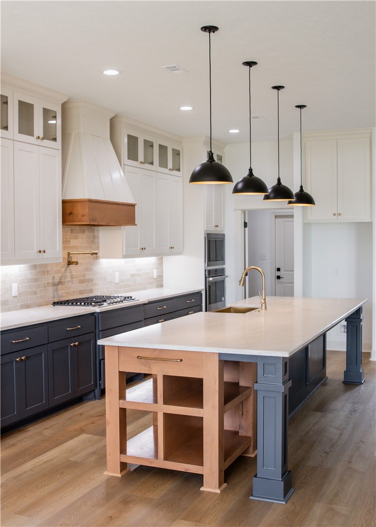 3201 Hunters Crossing Bryan, TX 77808 - Photo 6 of 40 Kitchen with gray cabinets, hanging light fixtures, light wood-type flooring, decorative backsplash, and premium range hood