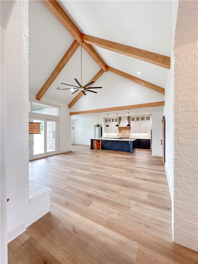 3201 Hunters Crossing Bryan, TX 77808 - Photo 7 of 40 Unfurnished living room with high vaulted ceiling, light wood-style flooring, beamed ceiling, and a ceiling fan