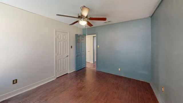 an empty room with wooden floor fan and windows