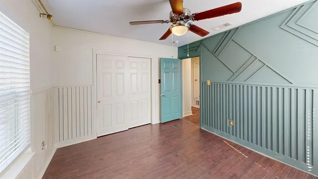 a view of a hallway with a ceiling fan and wooden floor
