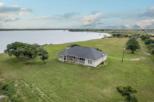 a view of a lake with a yard and large trees