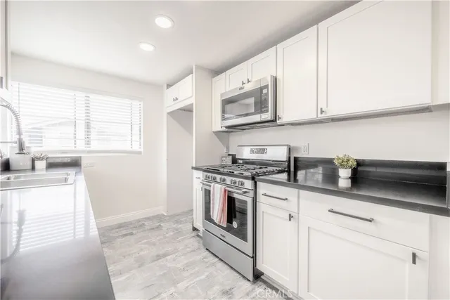 a kitchen with stainless steel appliances granite countertop white cabinets a sink and a stove