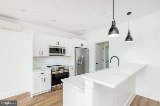 a kitchen with stainless steel appliances kitchen island a white counter top a stove a refrigerator with a sink and dishwasher