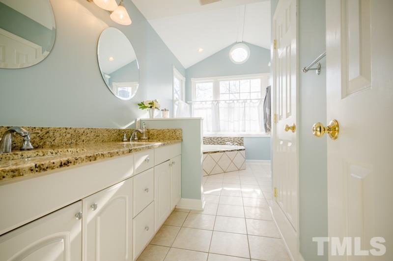 8321 Apple Orchard Way Raleigh, NC 27615 - Photo 15 of 24 a bathroom with a granite countertop sink a mirror and a bathtub
