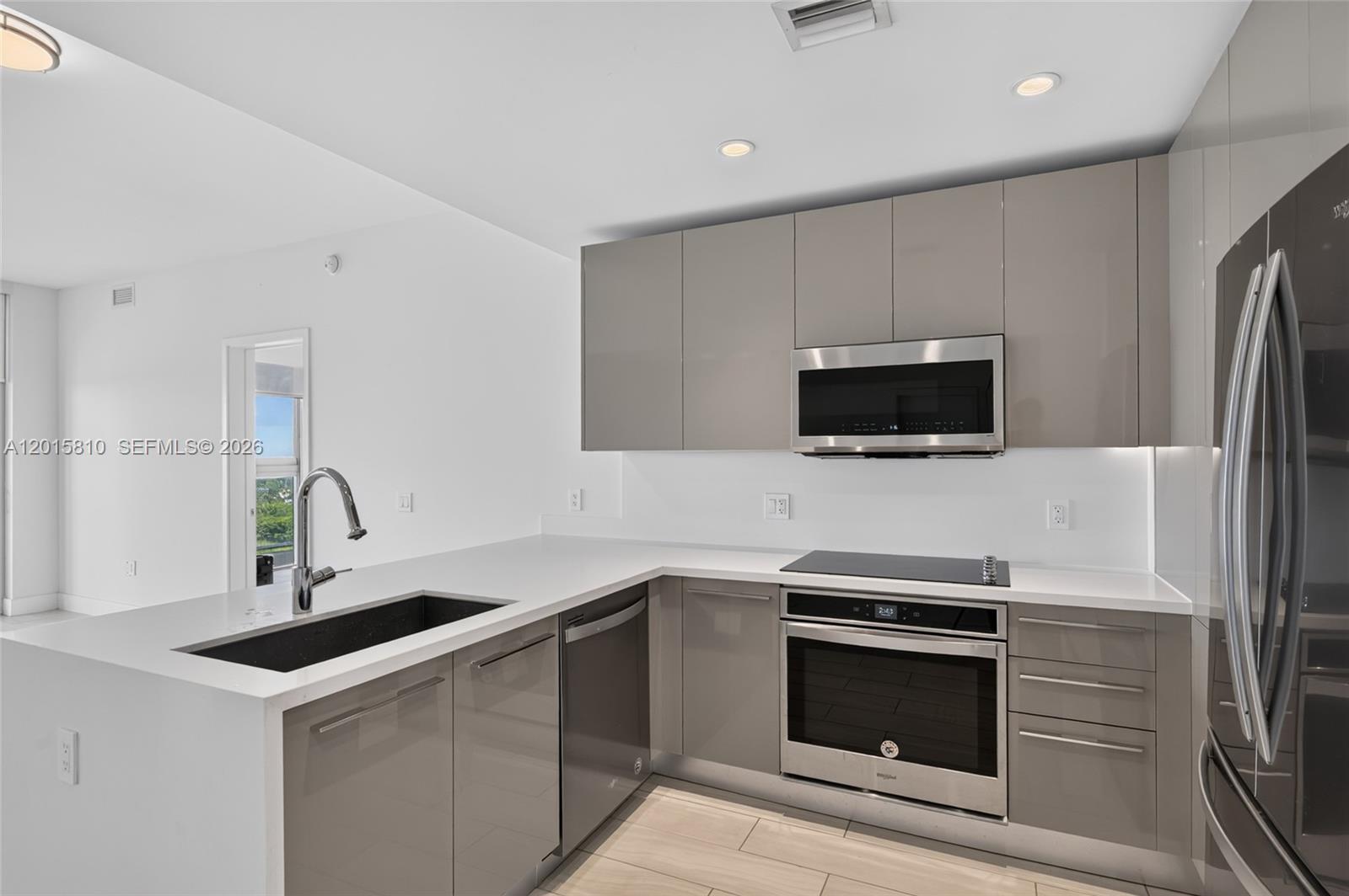 2000 Metropica Way, Unit 1902 Sunrise, FL 33323 - Photo 9 of 40 a kitchen with stainless steel appliances a stove microwave and sink
