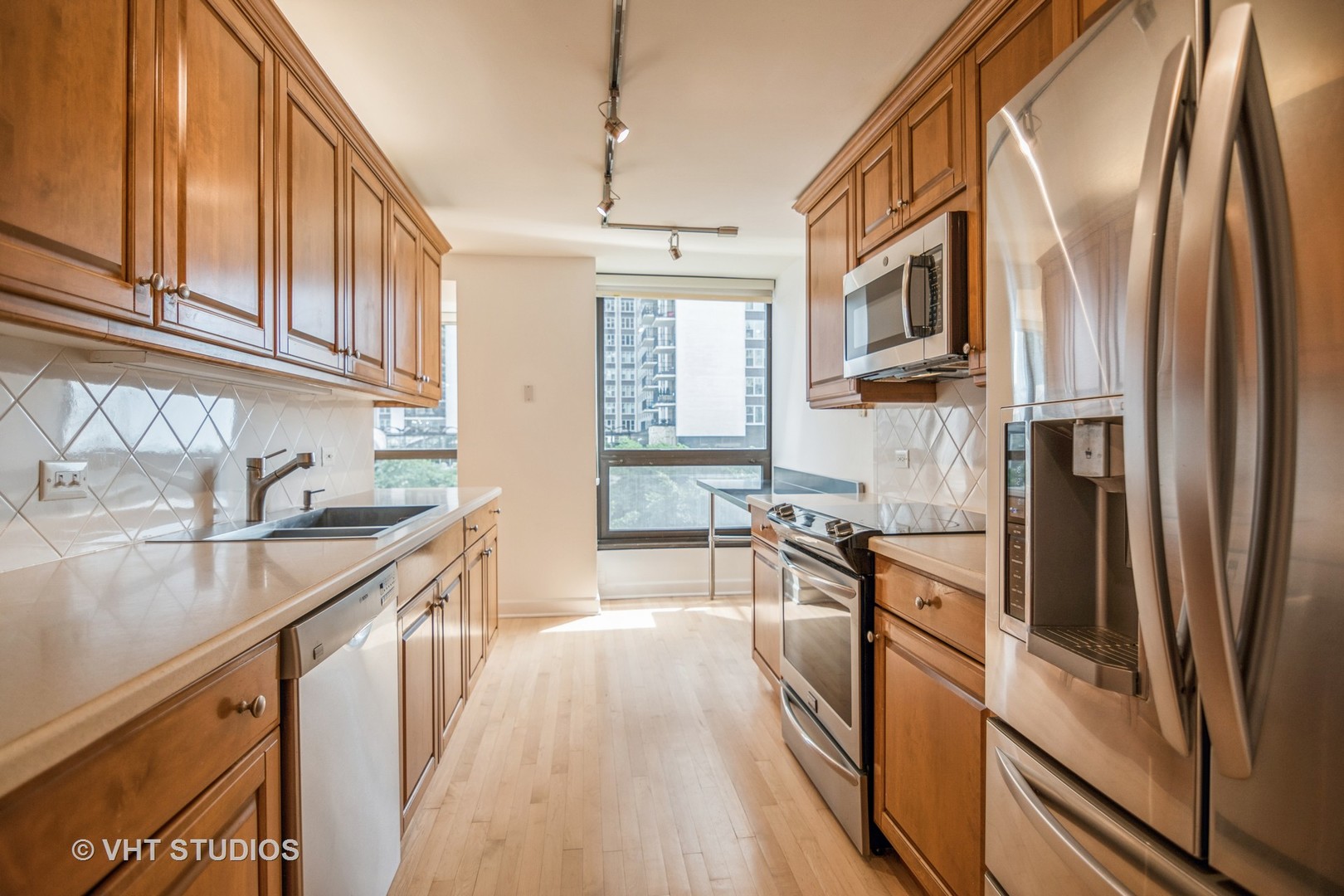 360 East Randolph Street, Unit 308 Chicago, IL 60601 - Photo 6 of 24 a kitchen with stainless steel appliances granite countertop a refrigerator a sink dishwasher a stove and white countertops with wooden floor