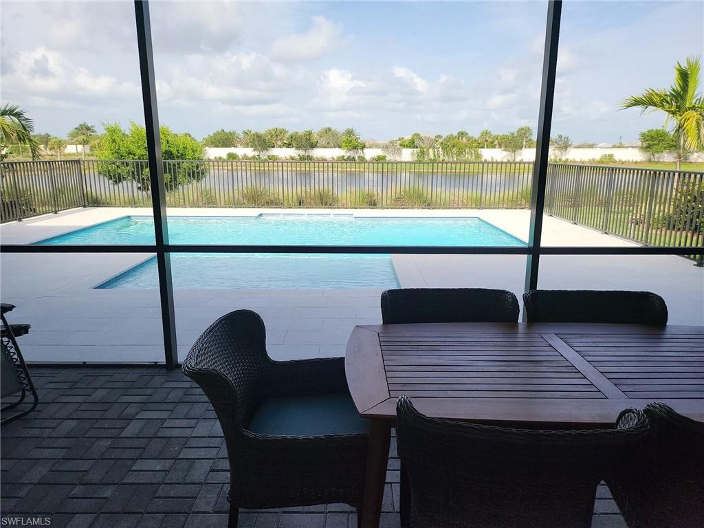 8770 Calypso Court Naples, FL 34113 - Photo 11 of 47 a wooden bench sitting on a table next to a lake