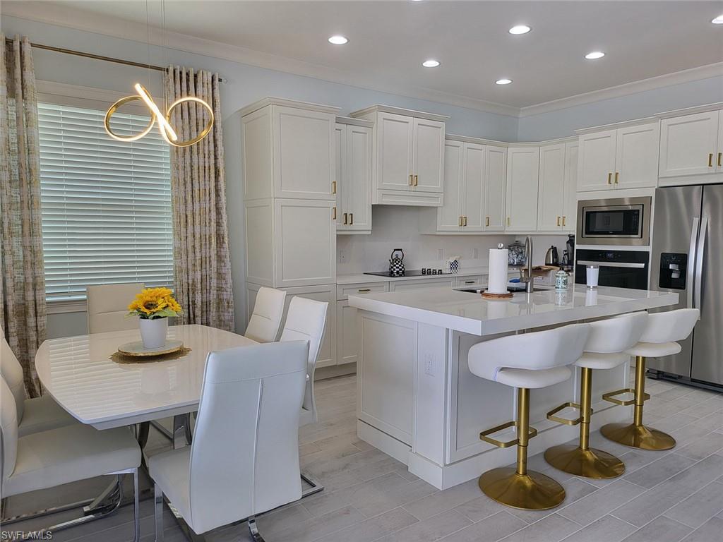 8770 Calypso Court Naples, FL 34113 - Photo 20 of 47 a kitchen with stainless steel appliances granite countertop a table chairs and a refrigerator