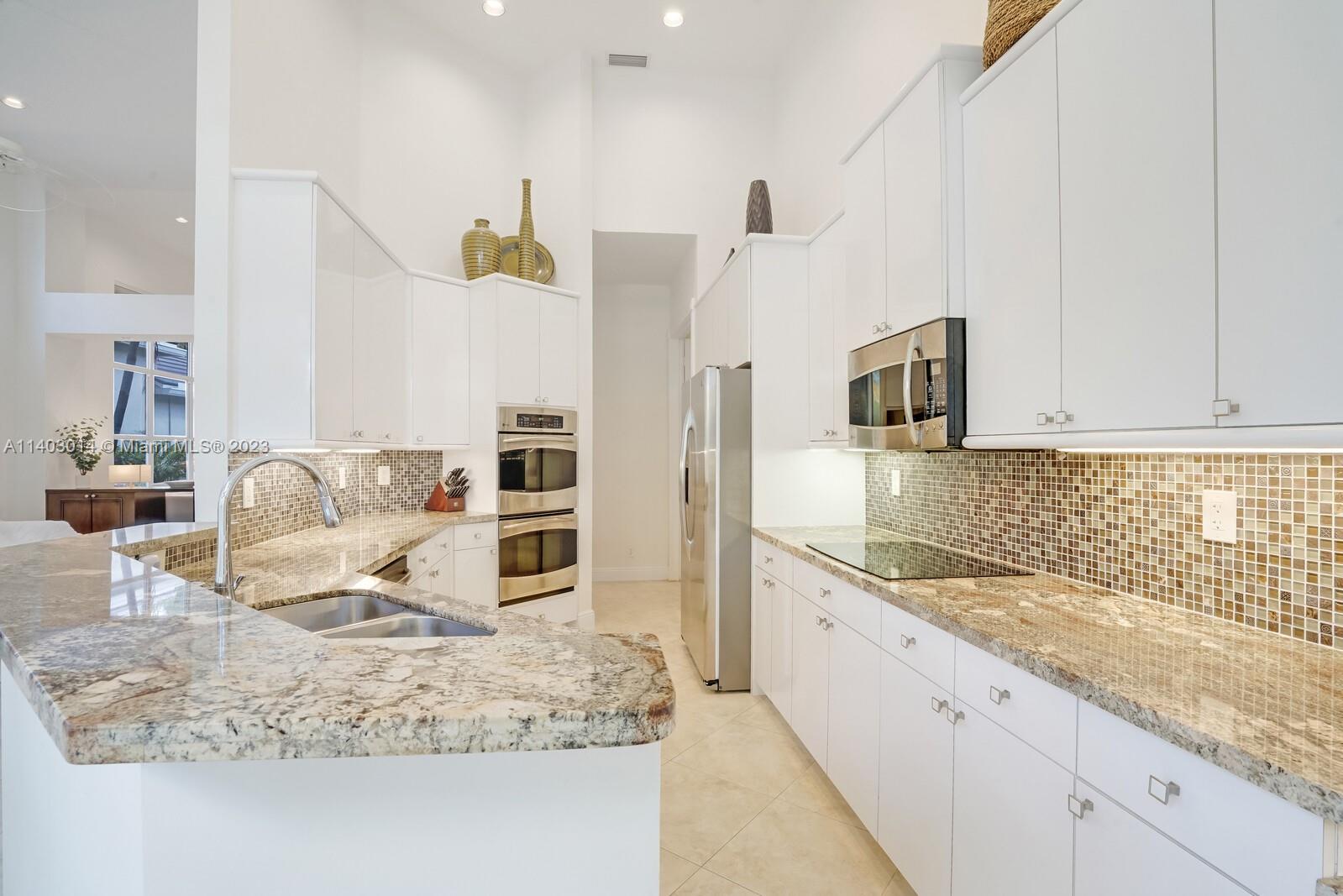 3322 Northwest 53rd Circle Boca Raton, FL 33496 - Photo 13 of 45 a kitchen with kitchen island granite countertop a sink stove and refrigerator