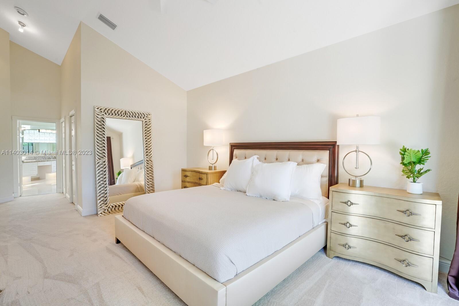 3322 Northwest 53rd Circle Boca Raton, FL 33496 - Photo 17 of 45 a bedroom with a large bed and paintings on the dresser