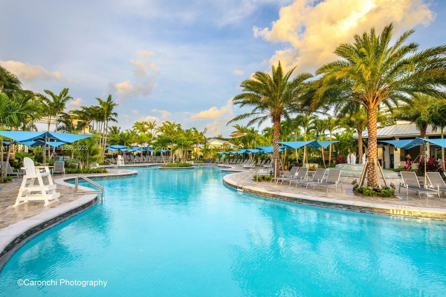 3322 Northwest 53rd Circle Boca Raton, FL 33496 - Photo 39 of 45 a view of a swimming pool with a lawn chairs under an umbrella