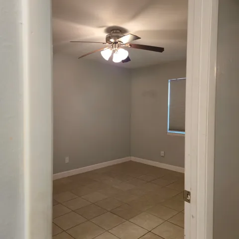 a view of an empty room and chandelier fan