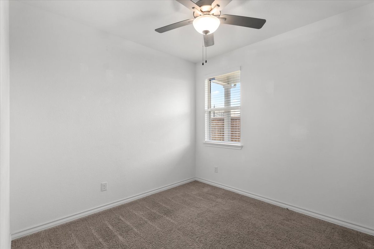 500 Stinchcomb Road Hutto, TX 78634 - Photo 25 of 37 A well-lit room with plush carpeting and a modern ceiling fan, offering a neutral canvas.