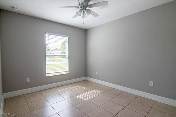 an empty room with a ceiling fan and window