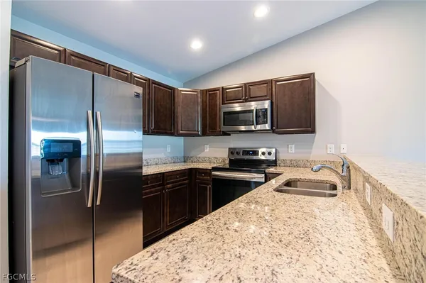 a kitchen with granite countertop a sink stove and refrigerator