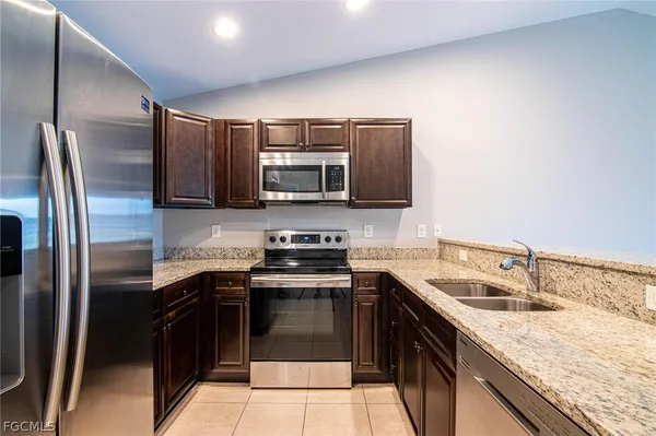 a kitchen with stainless steel appliances granite countertop a sink stove microwave and refrigerator