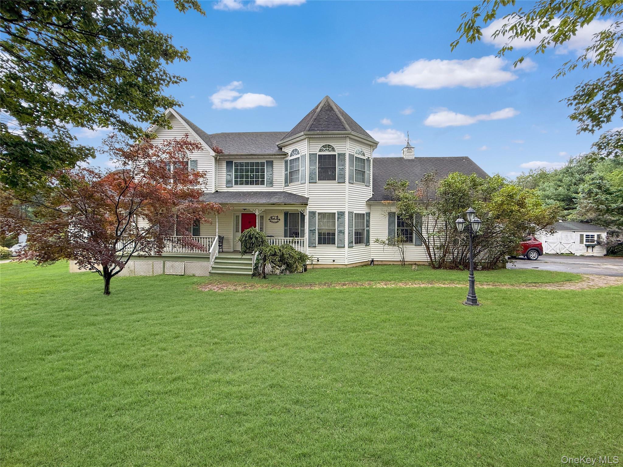 Victorian home with covered porch, a shingled roof, and a front yard