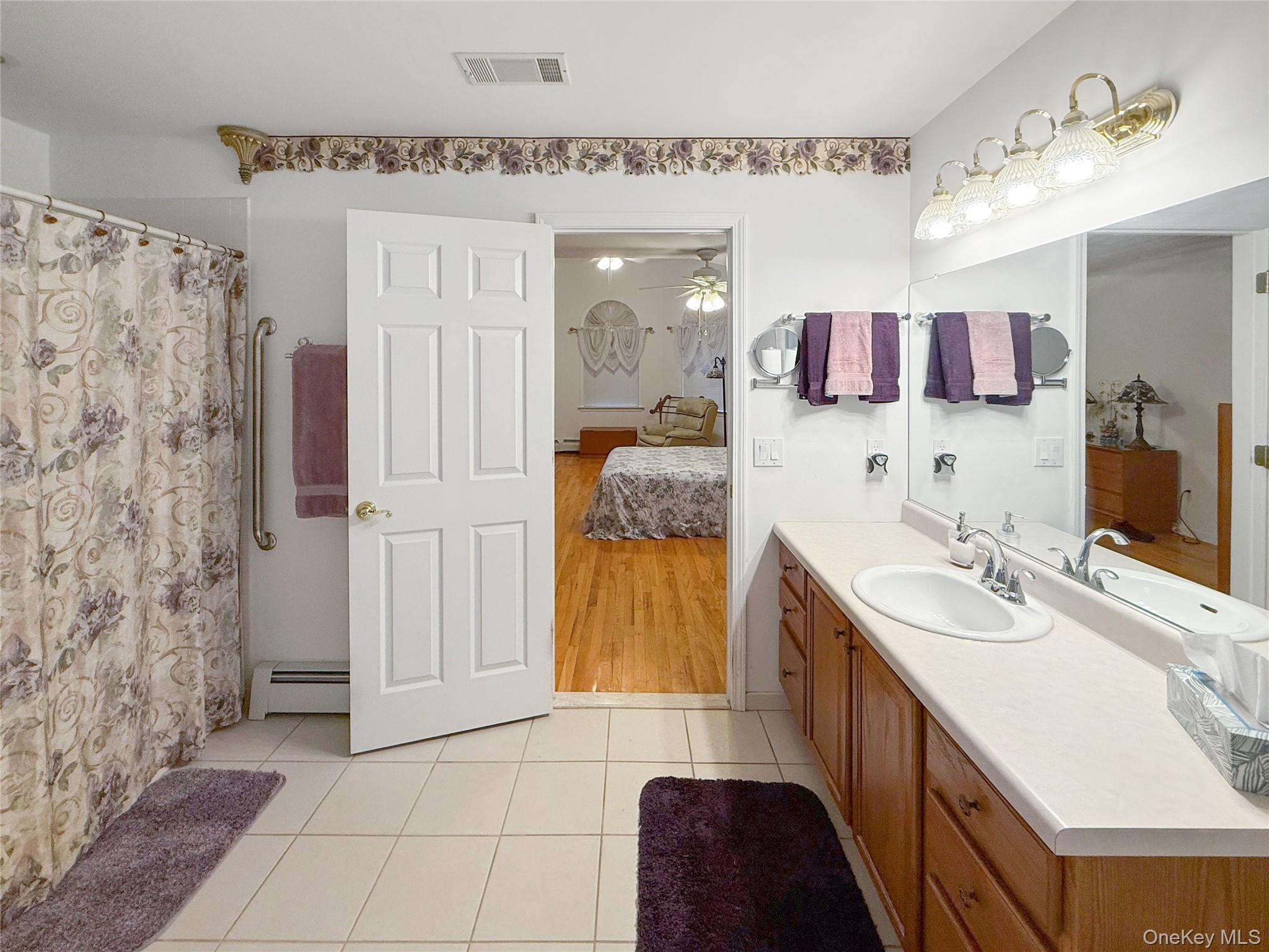 34 Feiertag Road Middletown, NY 10941 - Photo 23 of 28 Ensuite bathroom featuring tile patterned floors, vanity, ceiling fan, a baseboard heating unit, and curtained shower