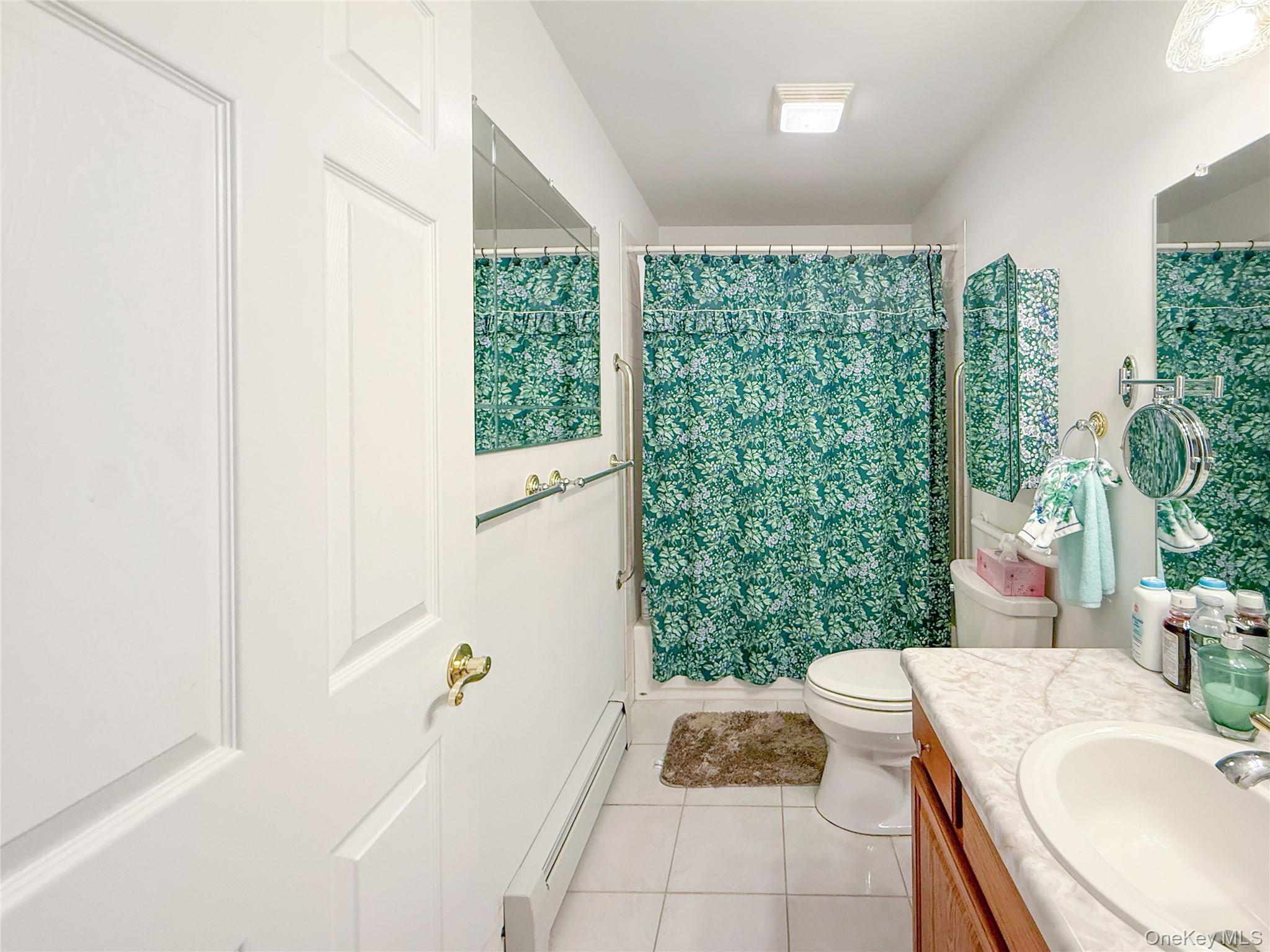 34 Feiertag Road Middletown, NY 10941 - Photo 27 of 28 Full bathroom featuring a baseboard heating unit, vanity, tile patterned flooring, and shower / tub combo with curtain