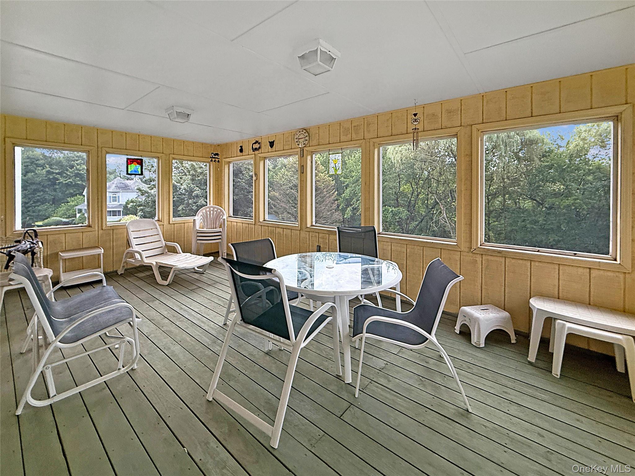 34 Feiertag Road Middletown, NY 10941 - Photo 5 of 28 Sunroom / solarium featuring wood walls, wood-type flooring, a deck, and outdoor dining space