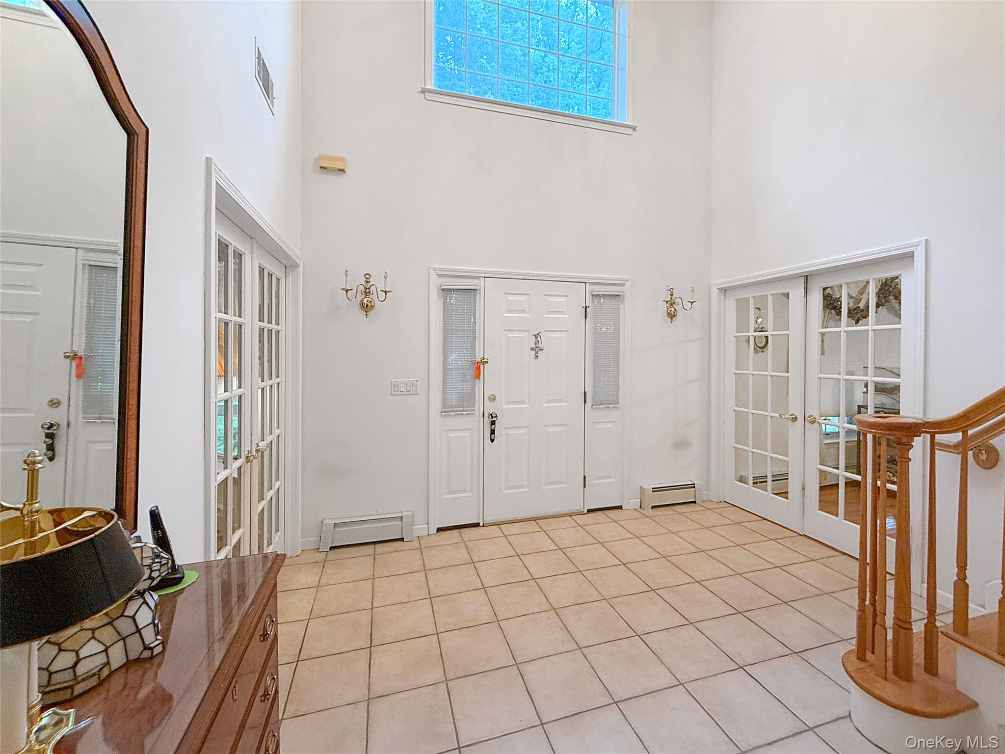 34 Feiertag Road Middletown, NY 10941 - Photo 8 of 28 Entrance foyer featuring french doors, light tile patterned floors, baseboard heating, and a high ceiling
