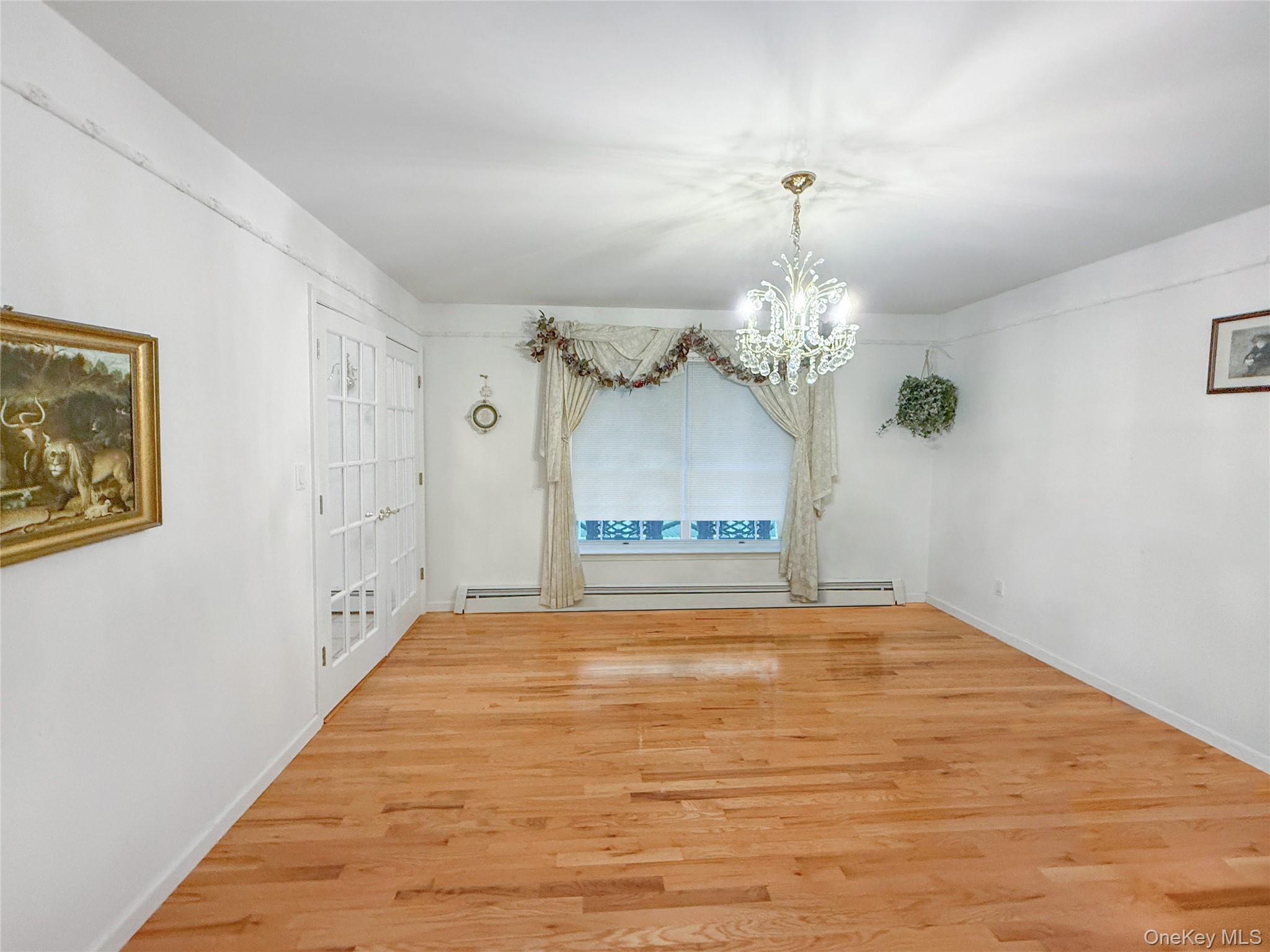 34 Feiertag Road Middletown, NY 10941 - Photo 9 of 28 Unfurnished dining area featuring wood finished floors, a chandelier, and a baseboard heating unit