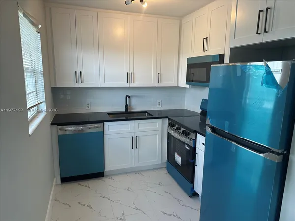 a kitchen with a sink a refrigerator and cabinets