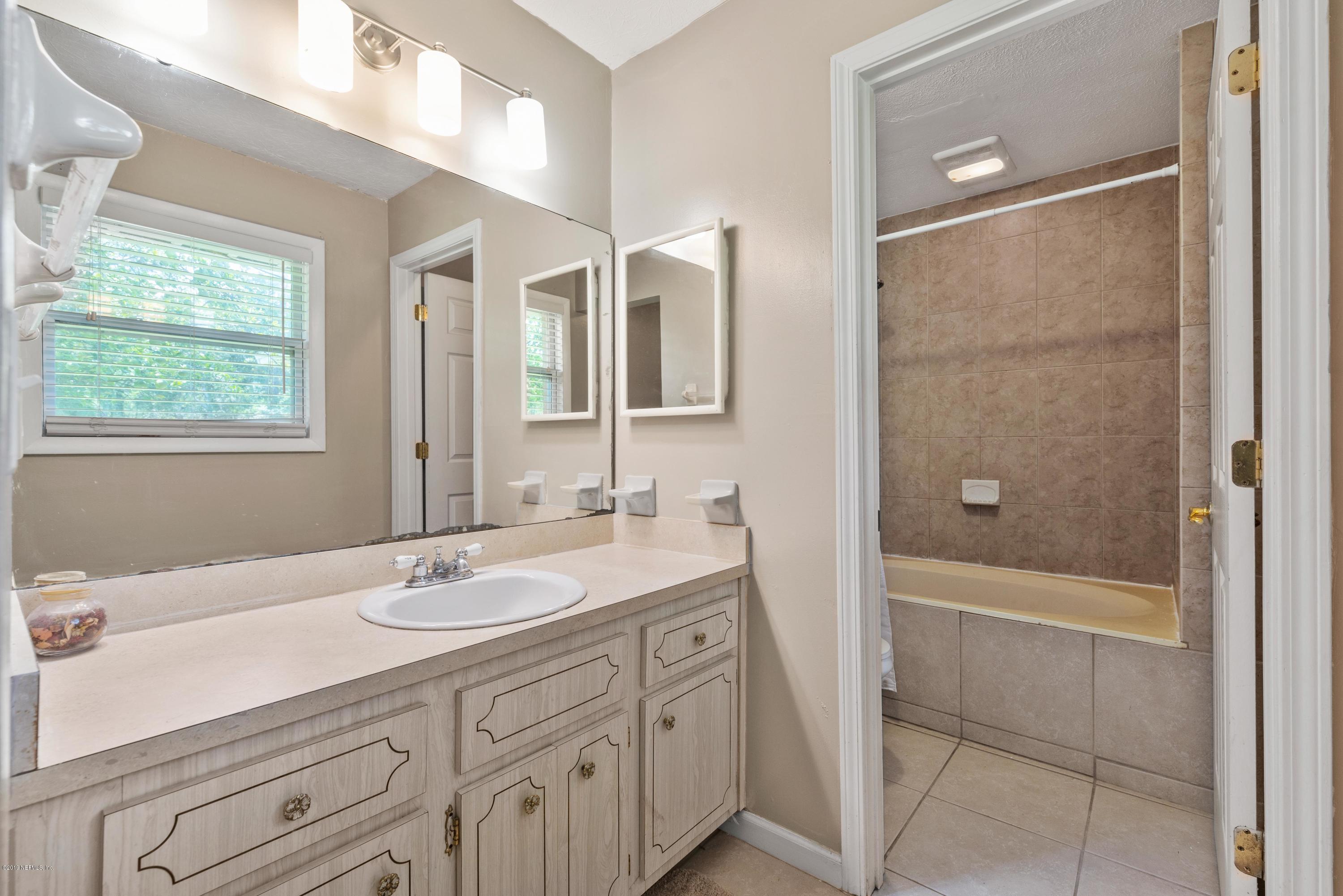 54152 Snyder Road Callahan, FL 32011 - Photo 25 of 39 a bathroom with a granite countertop sink a mirror and a bathtub