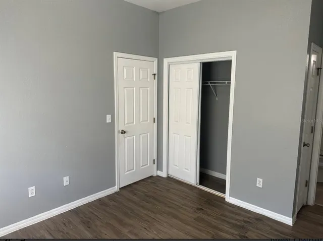 a view of an empty room with wooden floor and closet
