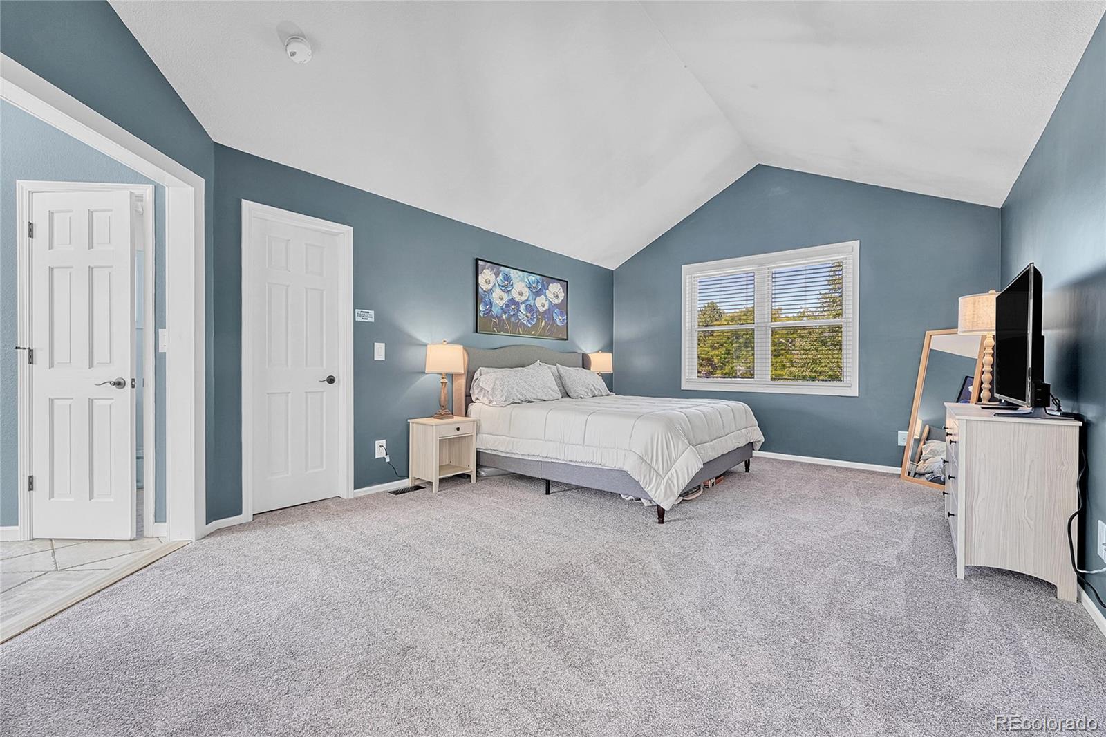 6722 Eagle Place Highlands Ranch, CO 80130 - Photo 21 of 47 a spacious bedroom with a bed a flat screen tv and window