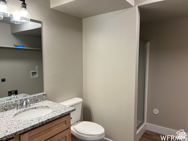 702 North 100 West Logan, UT 84321 - Photo 6 of 58 Bathroom featuring toilet, vanity, a textured ceiling, and a shower stall
