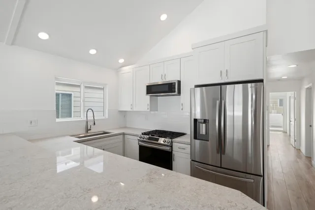 a kitchen with granite countertop a refrigerator stove and sink