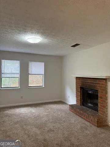 an empty room with windows and fireplace