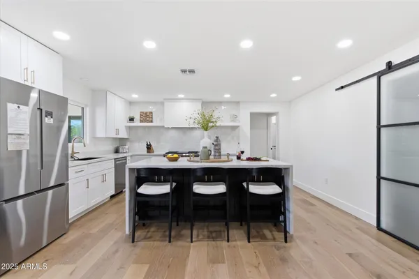 a kitchen with a sink a refrigerator and wooden floor