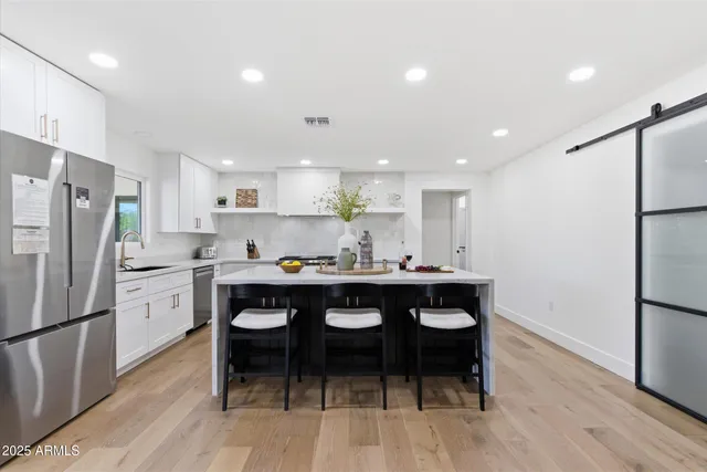 a kitchen with a sink a refrigerator and wooden floor